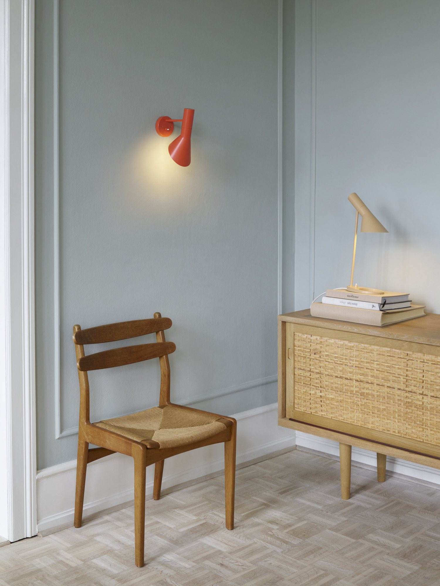 AJ Wall lamp in electric orange paired with AJ Mini in warm sand, soft lighting in a cozy setting, © 2025 Louis Poulsen.