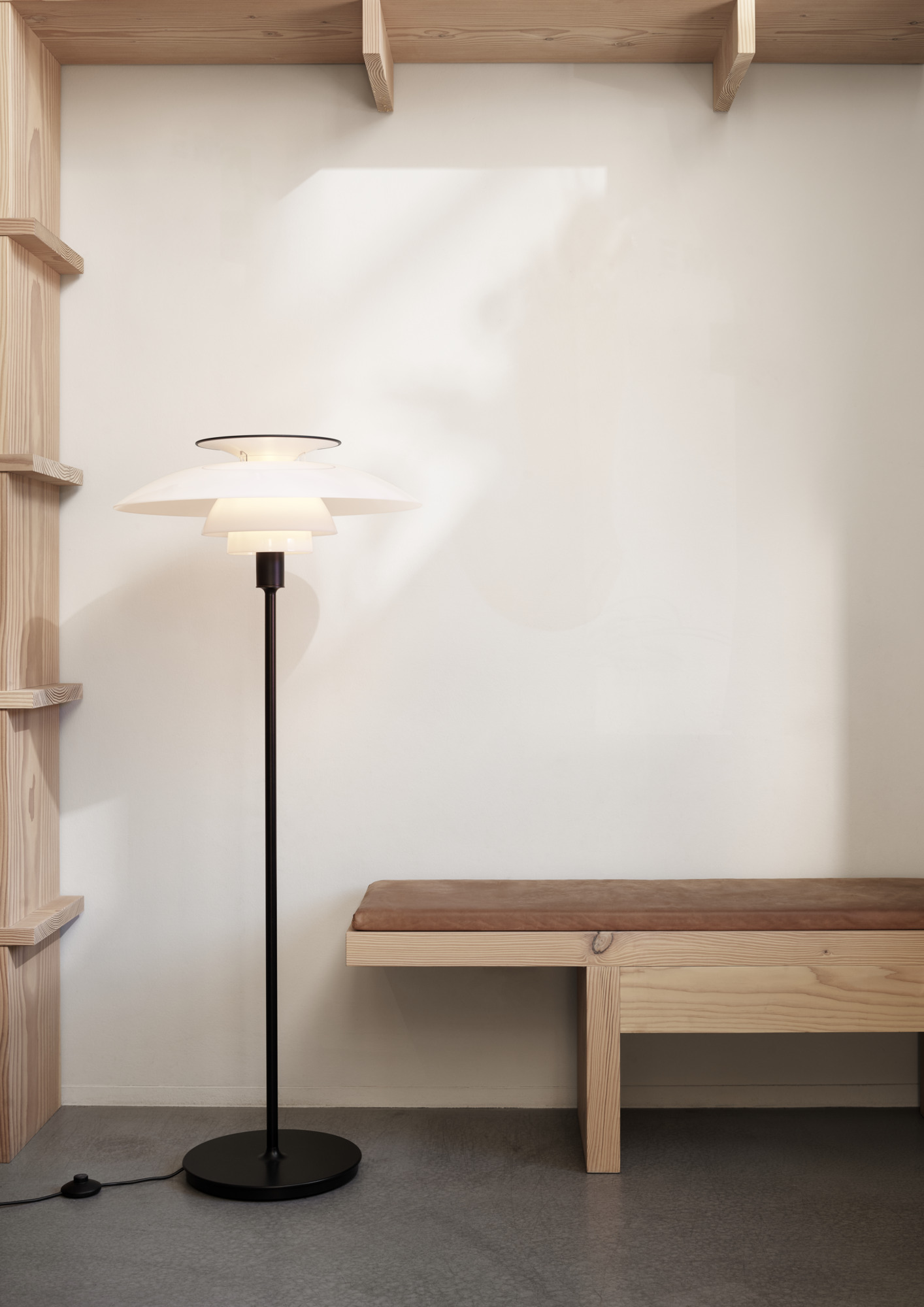 PH 80 floor lamp in white with a minimalist design, contrasting with the dark space, © 2025 Louis Poulsen.
