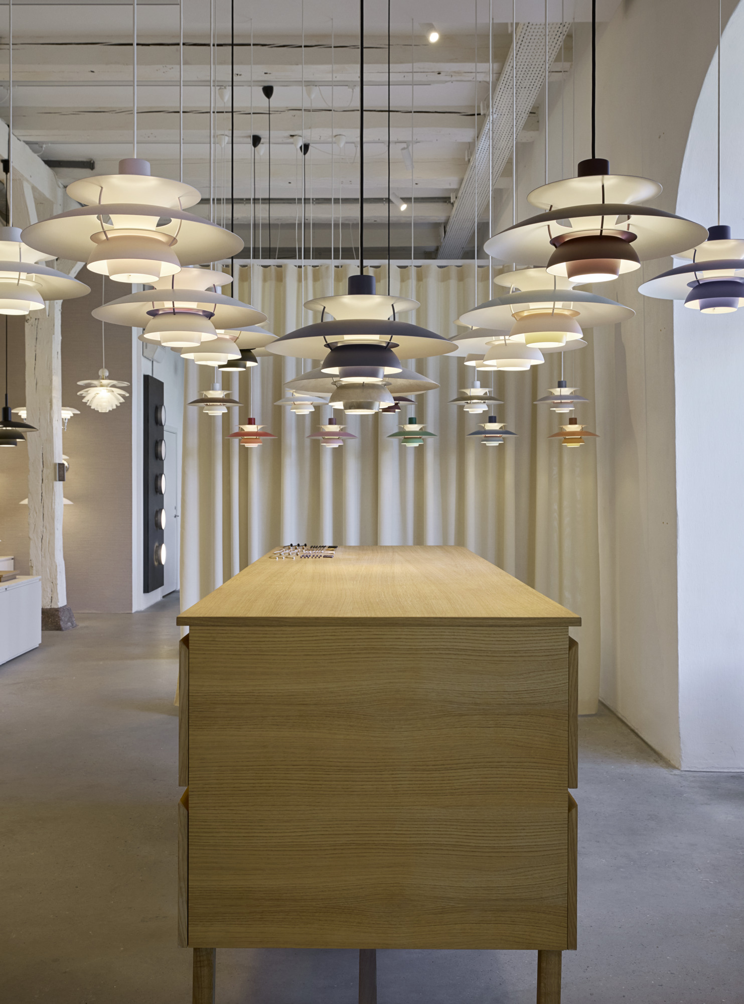 哥本哈根 Louis Poulsen 展厅内，多色 PH 5 吊灯悬挂于木桌上方, © 2025 Louis Poulsen.