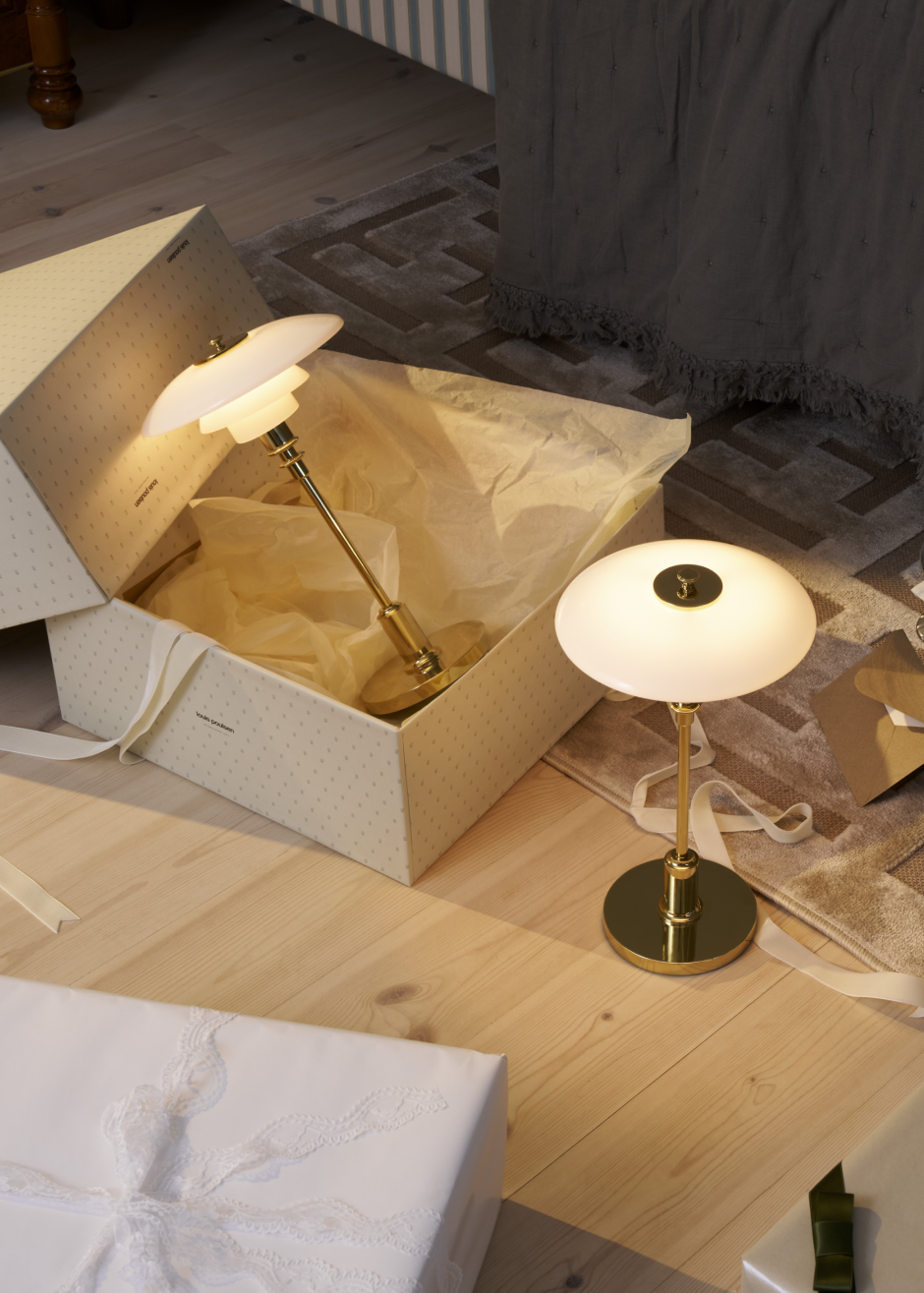 PH table lamp in gift box on a cozy bedroom floor, © 2025 Louis Poulsen.