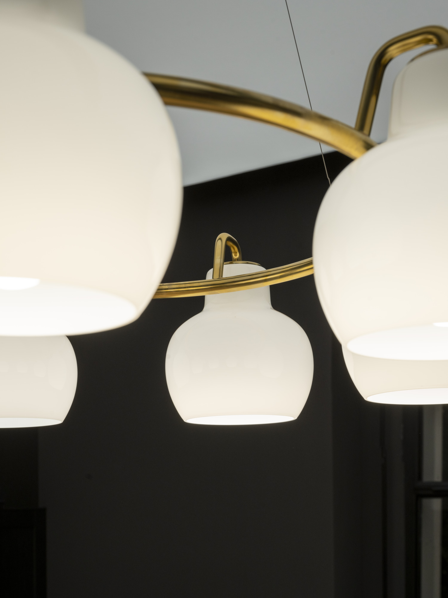 VL Ringcrown pendant with white globes and brass accents against a dark background, © 2025 Louis Poulsen.
