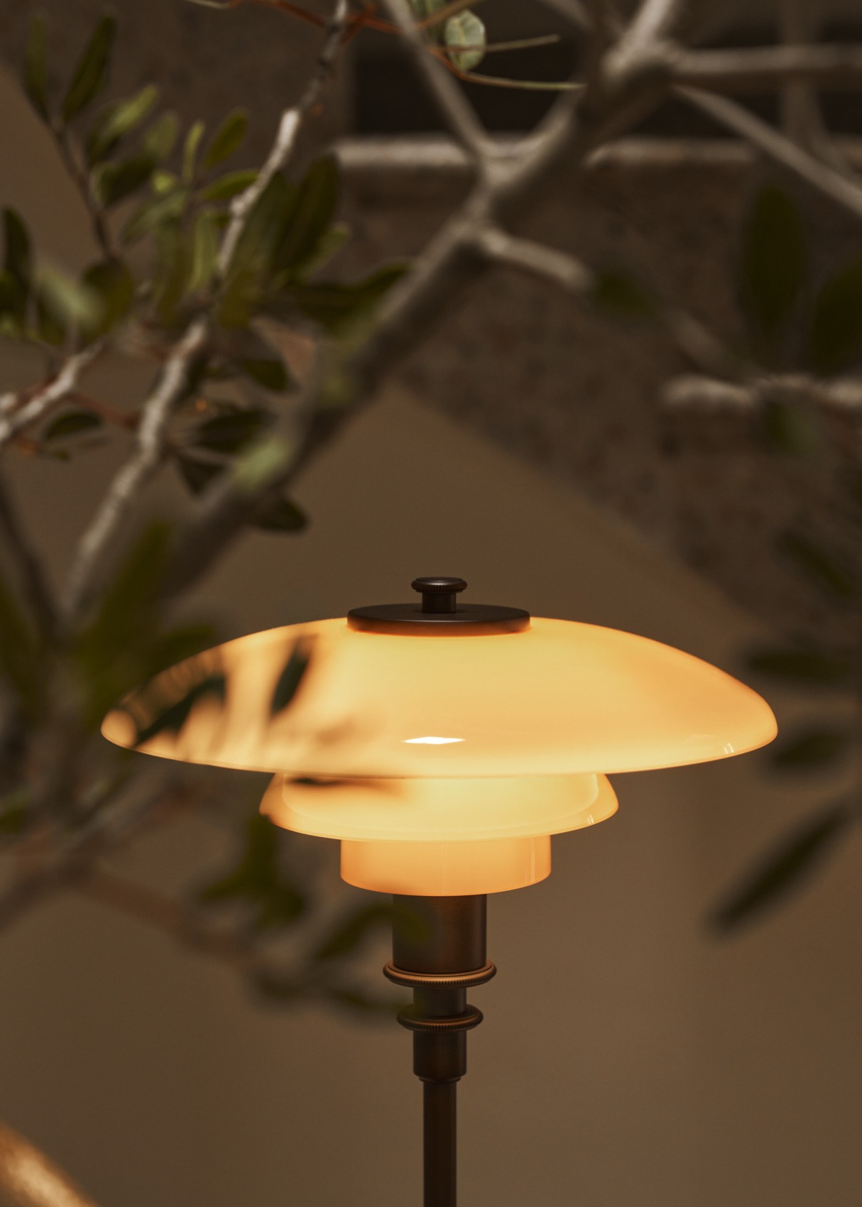 실내 식물 옆에서 따뜻한 빛을 비추는 PH 2/1 Table Lamp Limited Edition 2024, © 2025 Louis Poulsen.