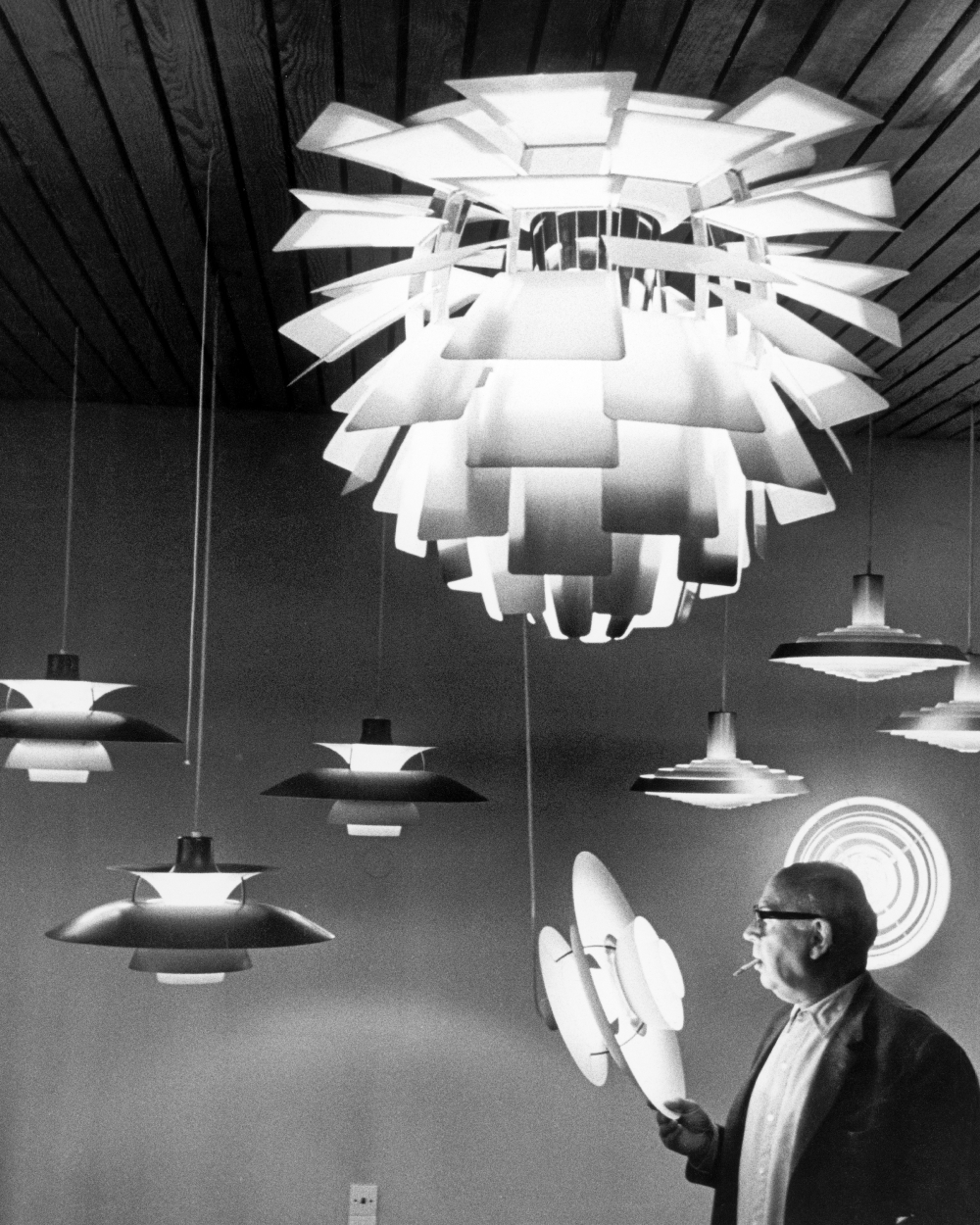 Poul Henningsen tarkastelee Artichoke- ja PH-valaisimia showroomissa, © 2025 Louis Poulsen.