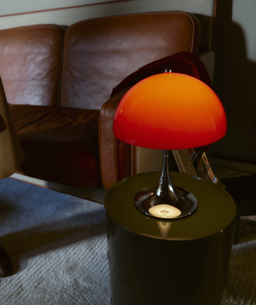 Panthella 250 Portable の Red が温かな室内のサイドテーブルに置かれる, © 2025 Louis Poulsen.