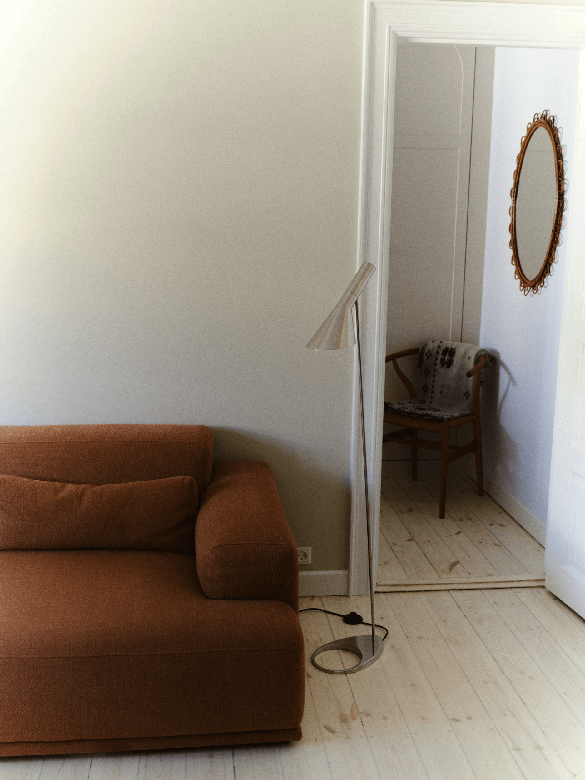 AJ Stehleuchte neben Sofa mit gerichtetem Leselicht im Wohnzimmer, © 2025 Louis Poulsen.