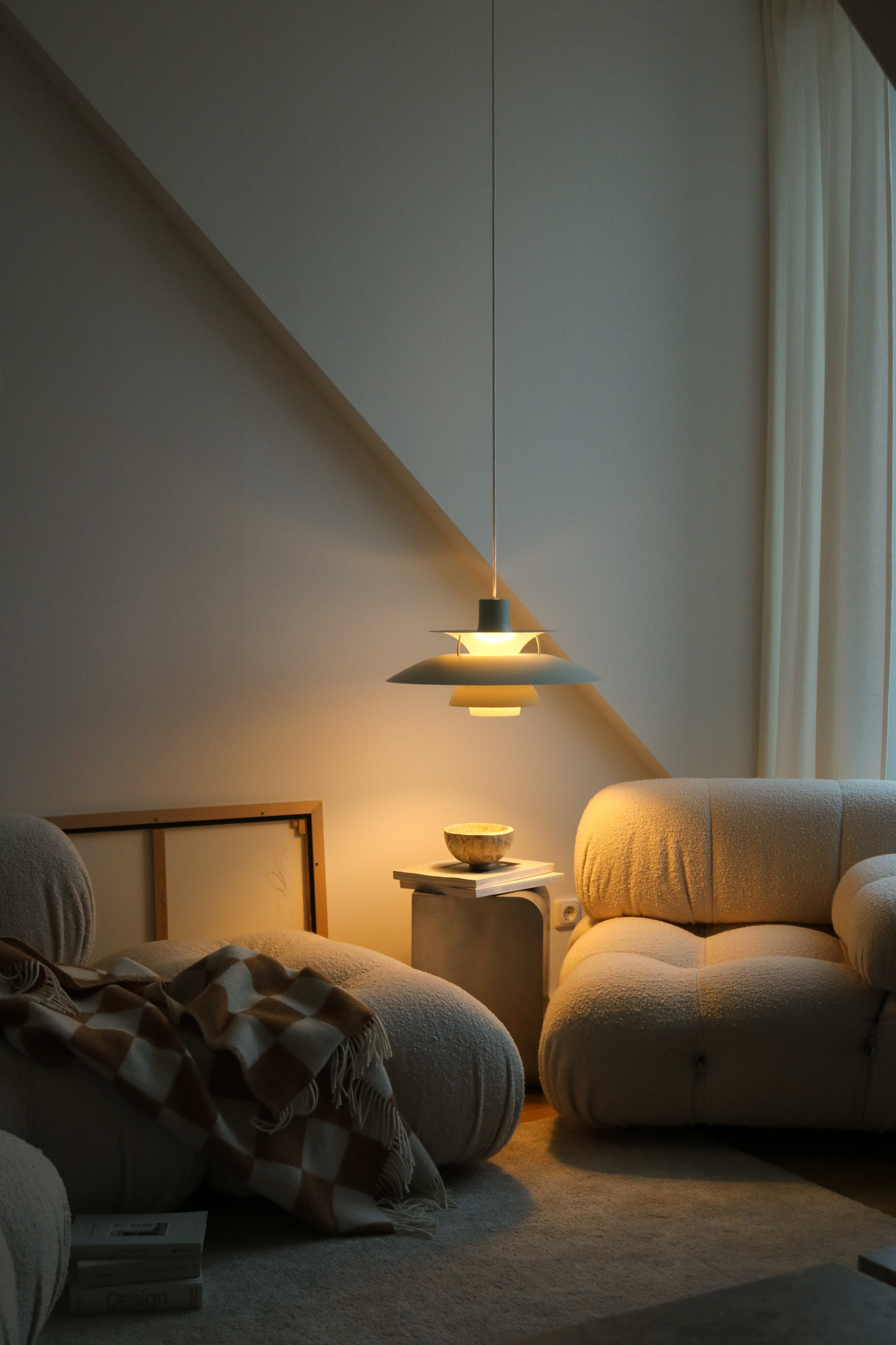 PH 5 pendant lamp glowing in cozy living room corner, © 2025 Louis Poulsen.